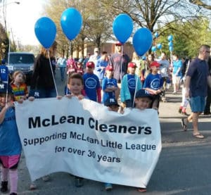 Children in a parade holding a banner McLean Cleaners